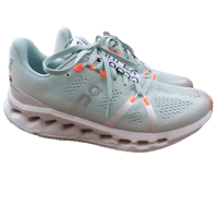 a women's running shoe in mint green and orange