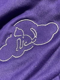 a close up of a purple t - shirt with a white elephant embroidered on it