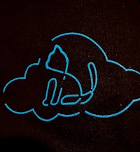 a black t - shirt with a cat on a cloud