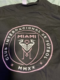 a black t - shirt with a pink logo on it